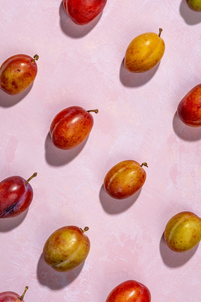 Victoria plums on a pink painted background with stone shadows - Food Photographer Liverpool UK